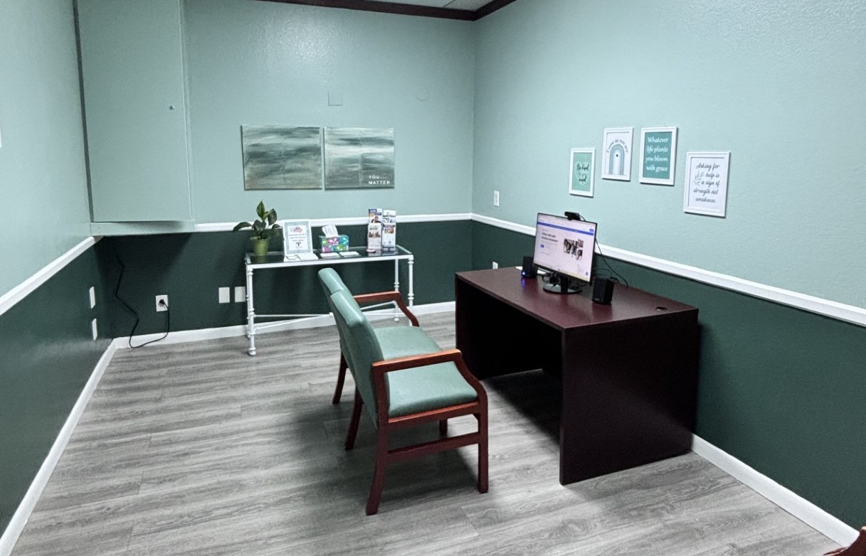 Private consultation room with sage-green walls and two guest chairs at the Mental Wellness Center.