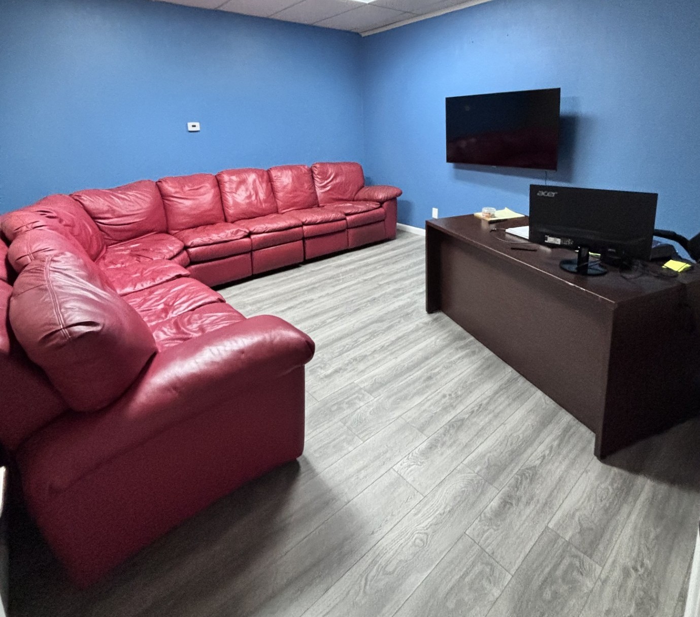 Counseling room with a large red sectional sofa and a desk.