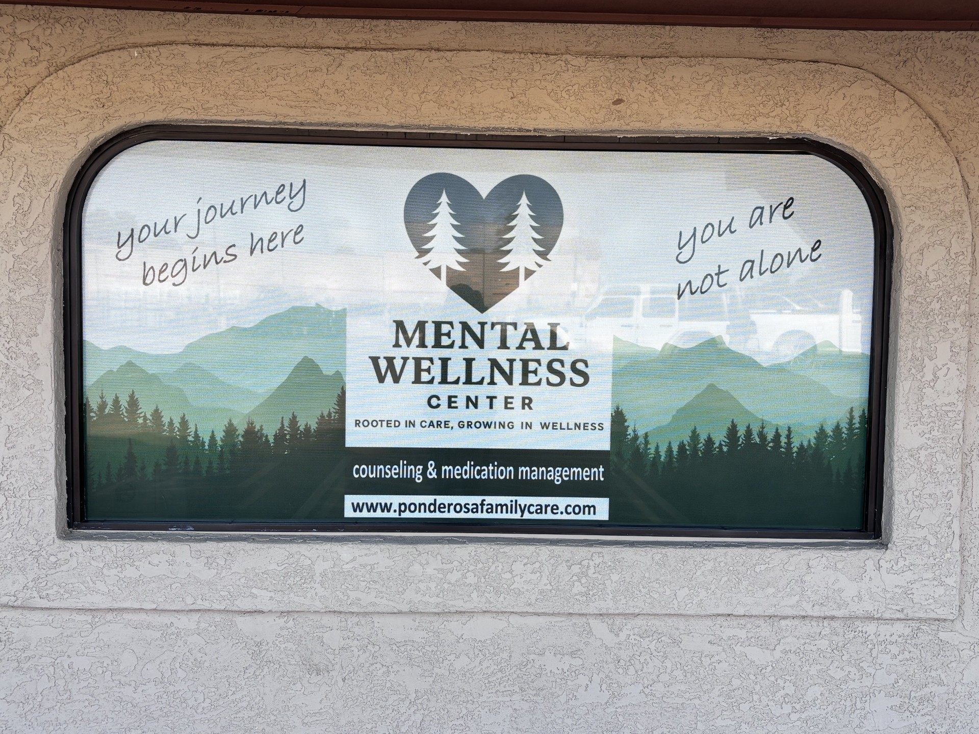 The Mental Wellness Center sign with pine trees and the words counseling and medication management.